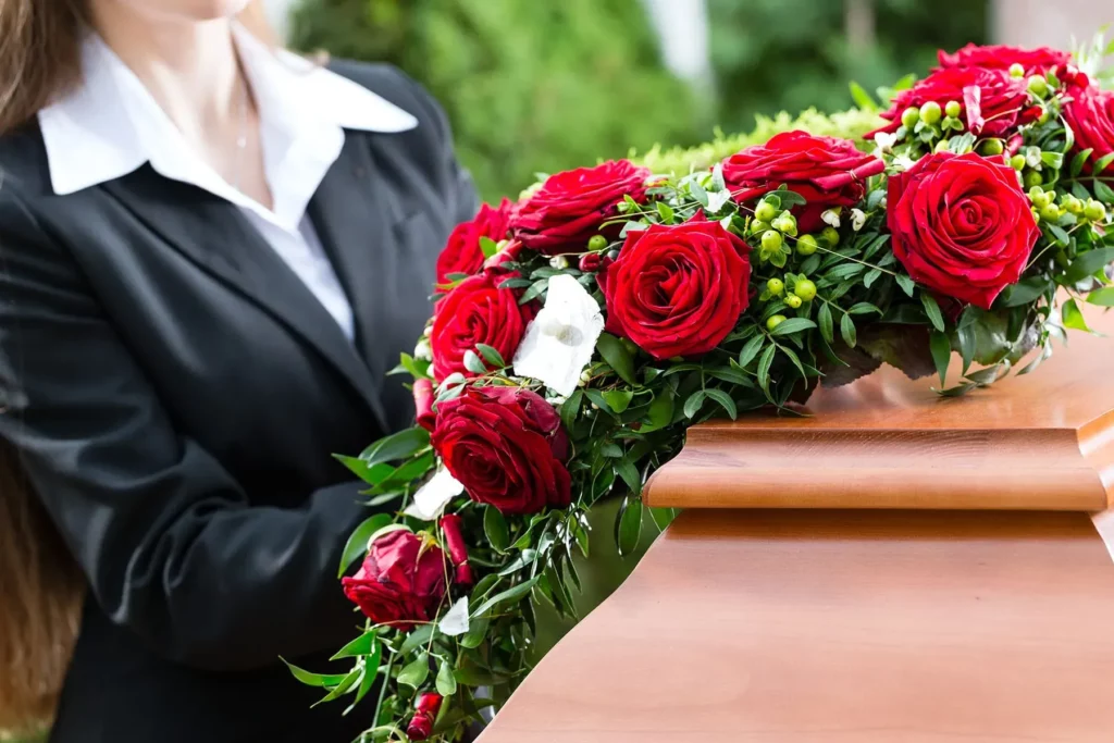 Composition florale de roses rouges disposée sur un cercueil en bois.