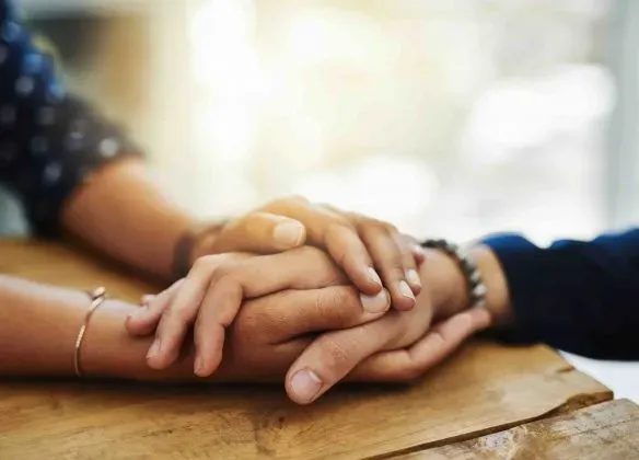 Mains croisées posées l'une sur l'autre en signe de soutien, de réconfort et d'empathie.