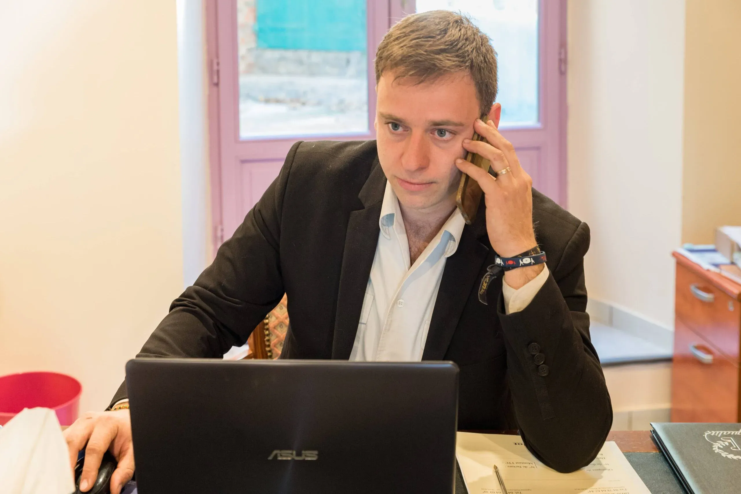 Conseiller funéraire au téléphone devant un ordinateur dans son bureau.