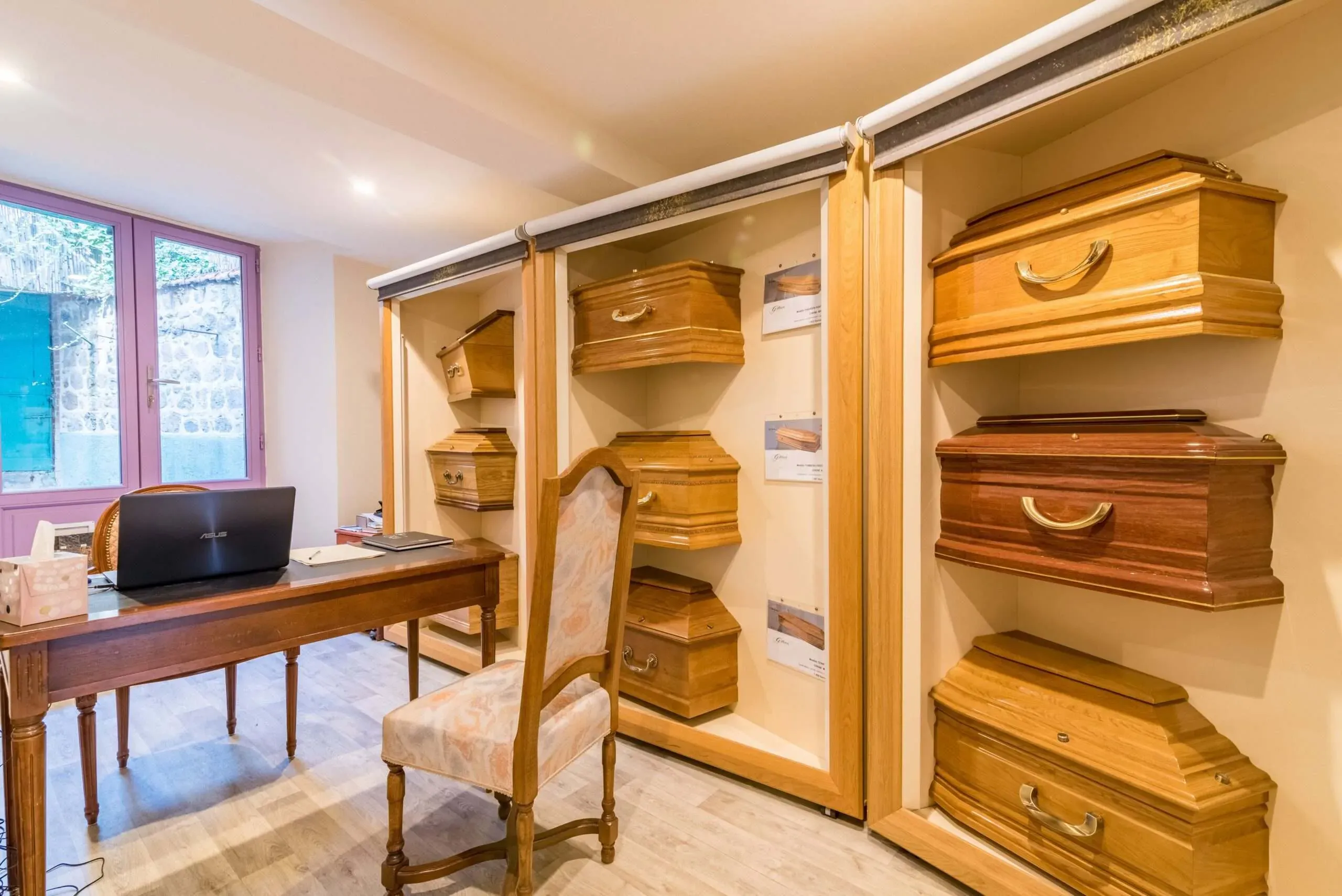 Salle d'exposition présentant un choix de modèles de cercueils en bois.